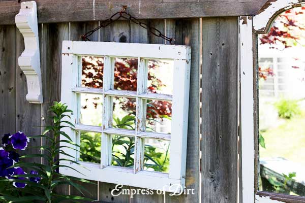 White framed mirror on garden fence.