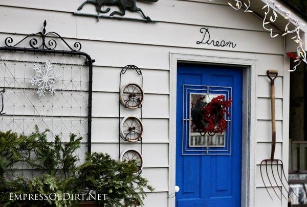 A shed decorated for winter with greenery in a window box.