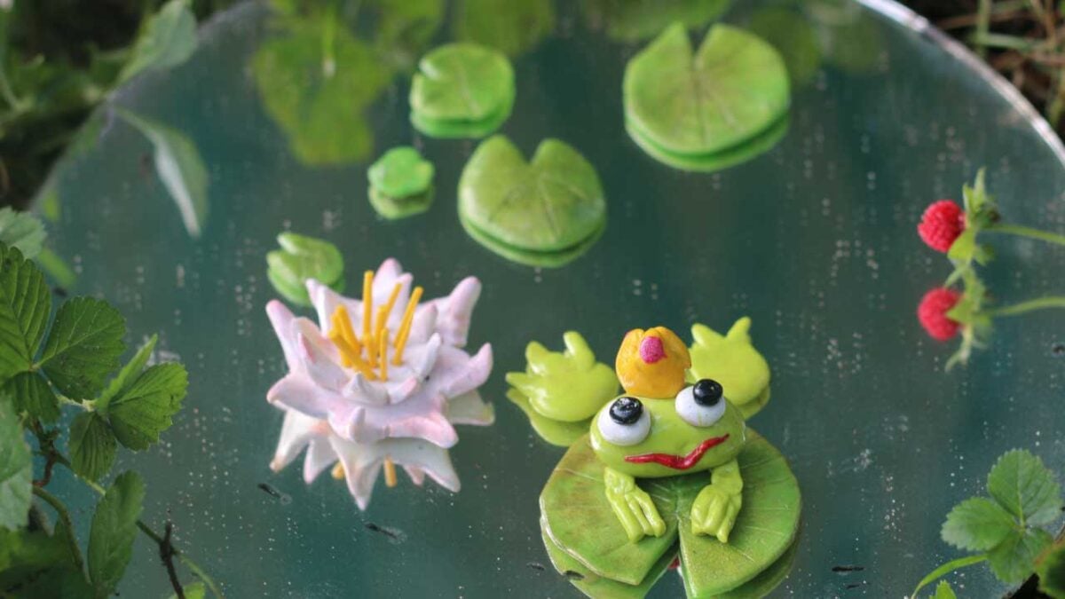 Homemade polymer clay fairy garden accessories including a frog and lily pad.