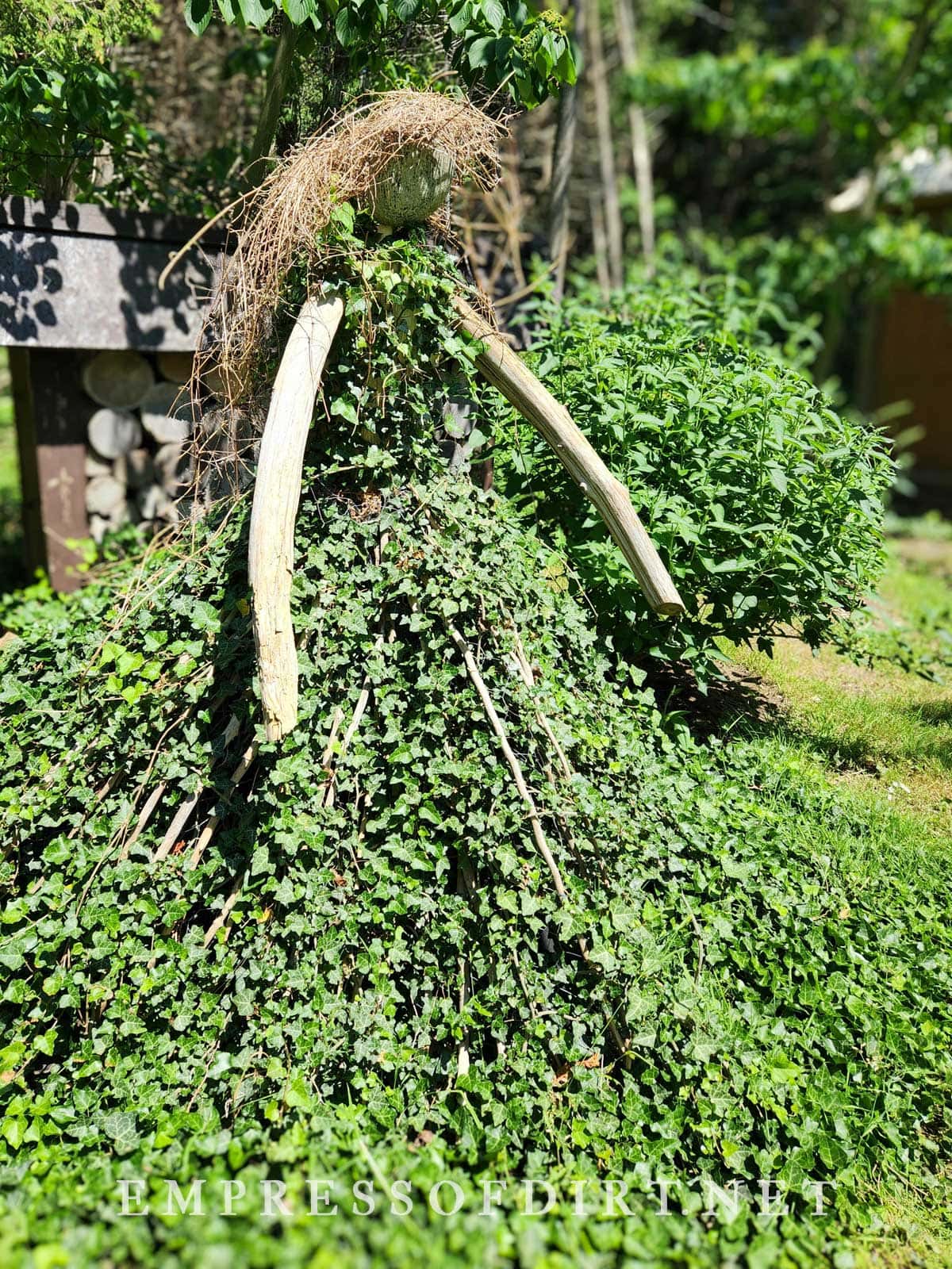 Overgrown vines form the body and dress of this garden art woman