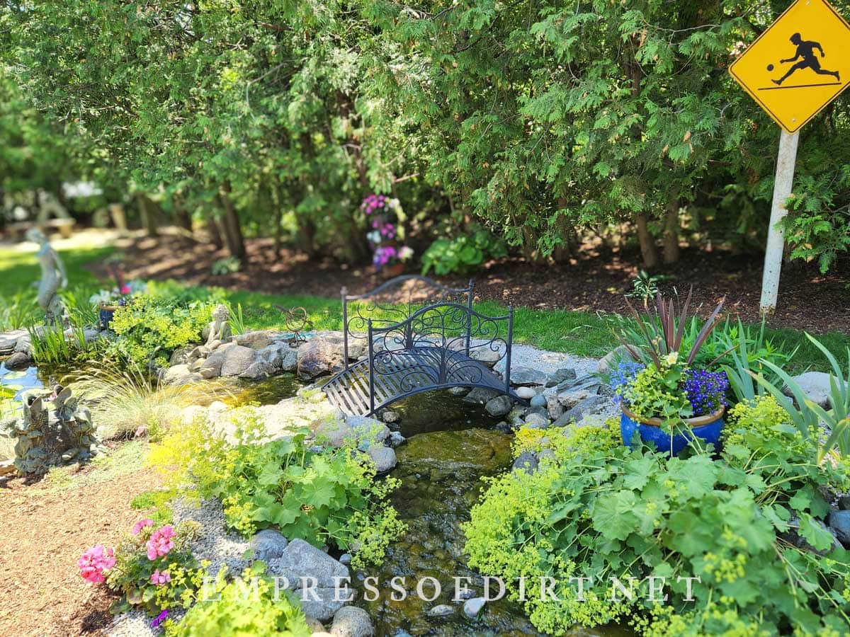 Black metal bridge over garden pond