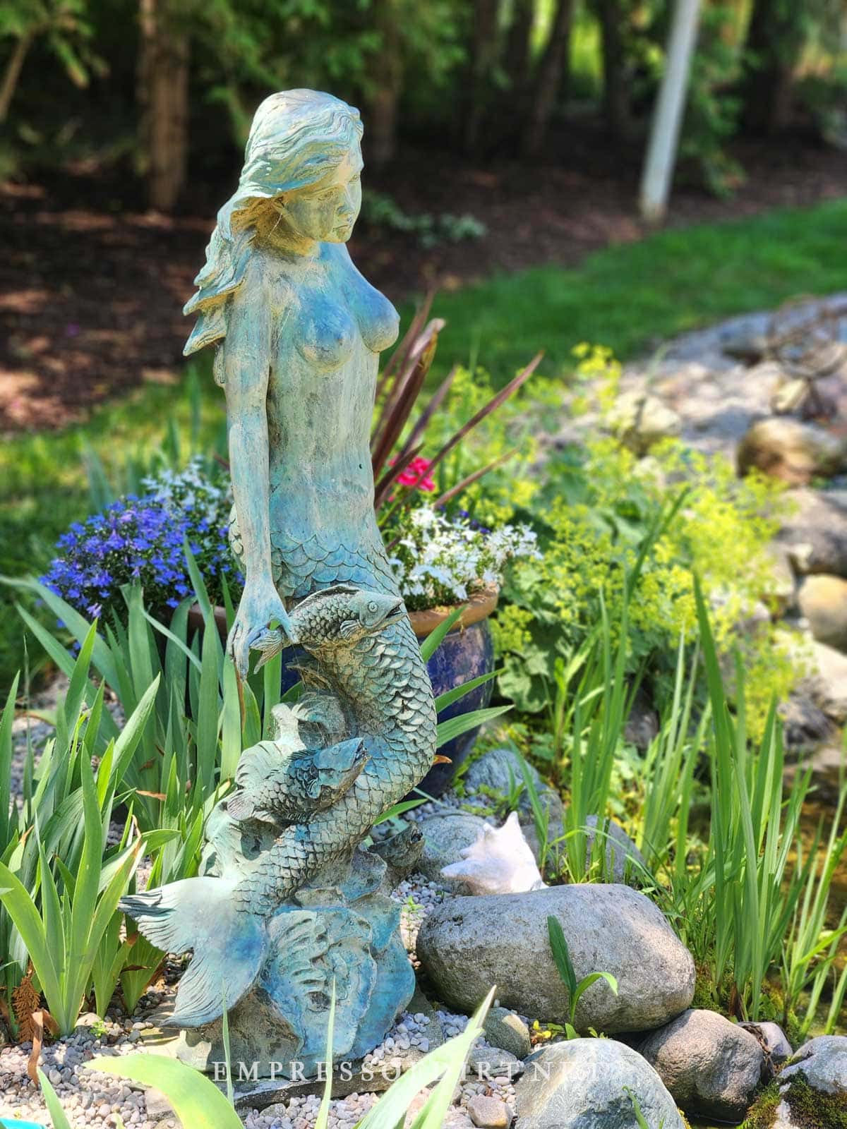 Mermaid statue by garden pond