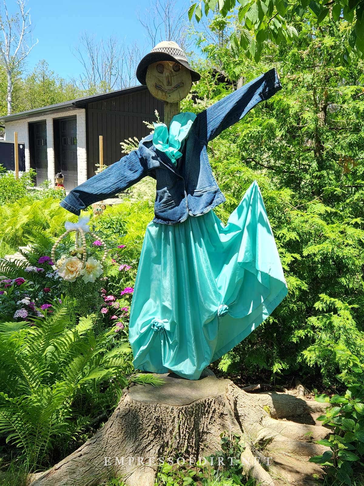 Woman scarecrow in a flowing blue dress with outstretched arms and hat