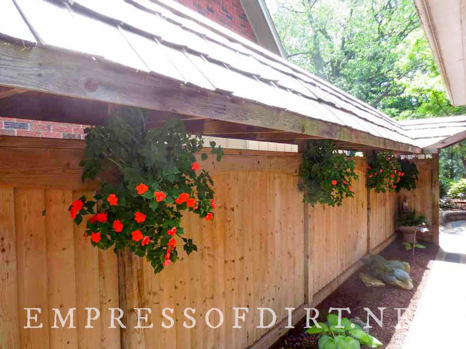 Flower gaskets hanging along garden fence.