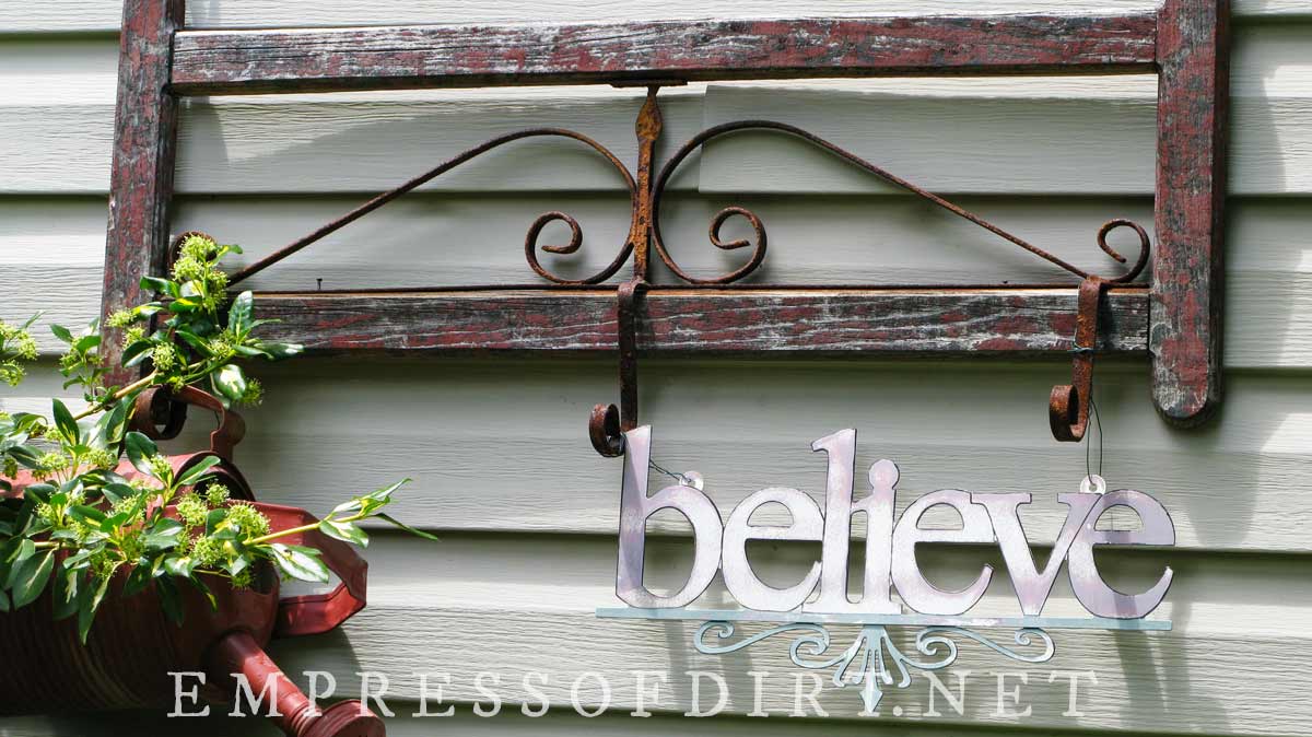 Repurposed garden art and sign reading believe.